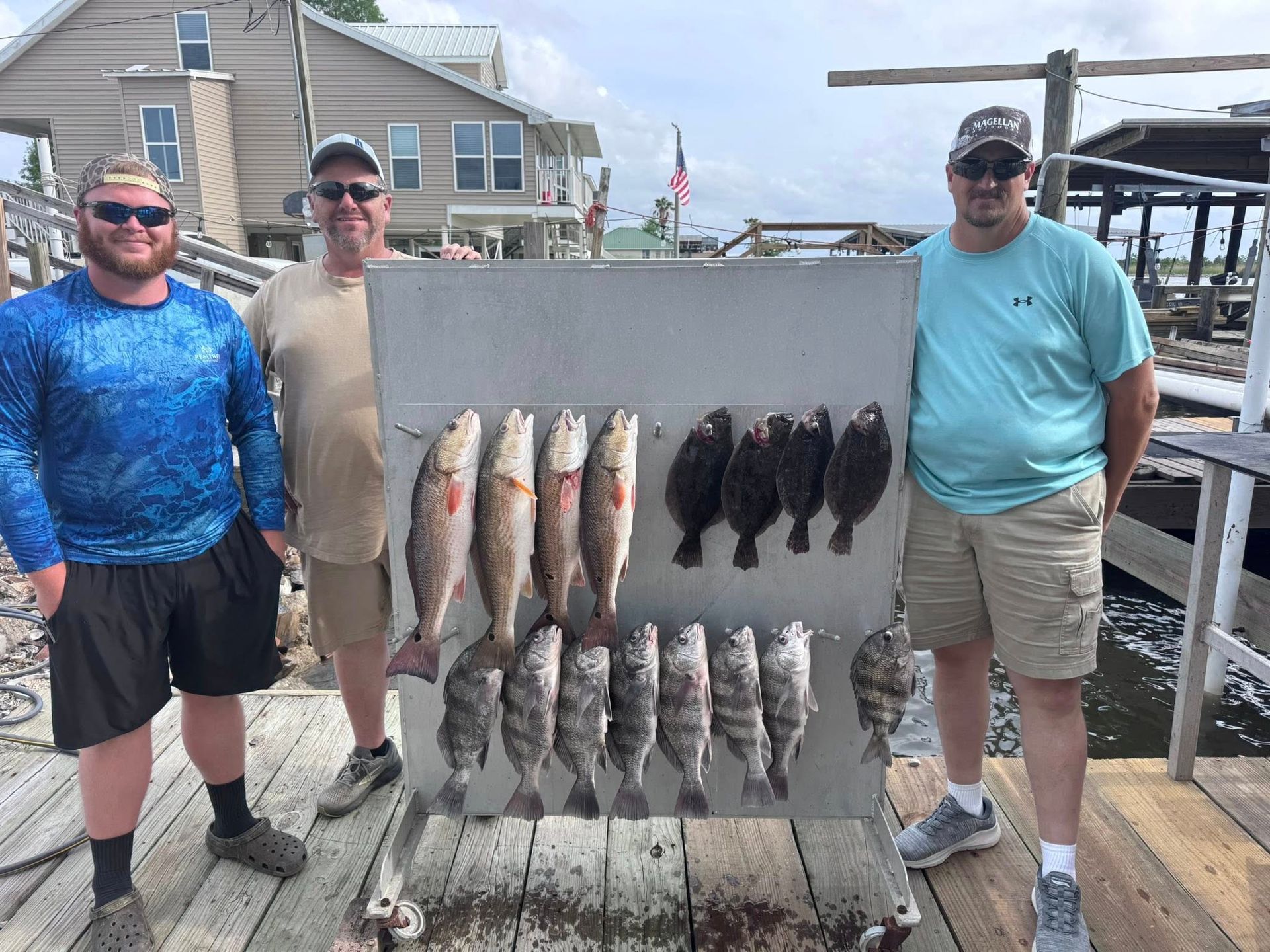 Three men are standing on a dock holding a display of fish.