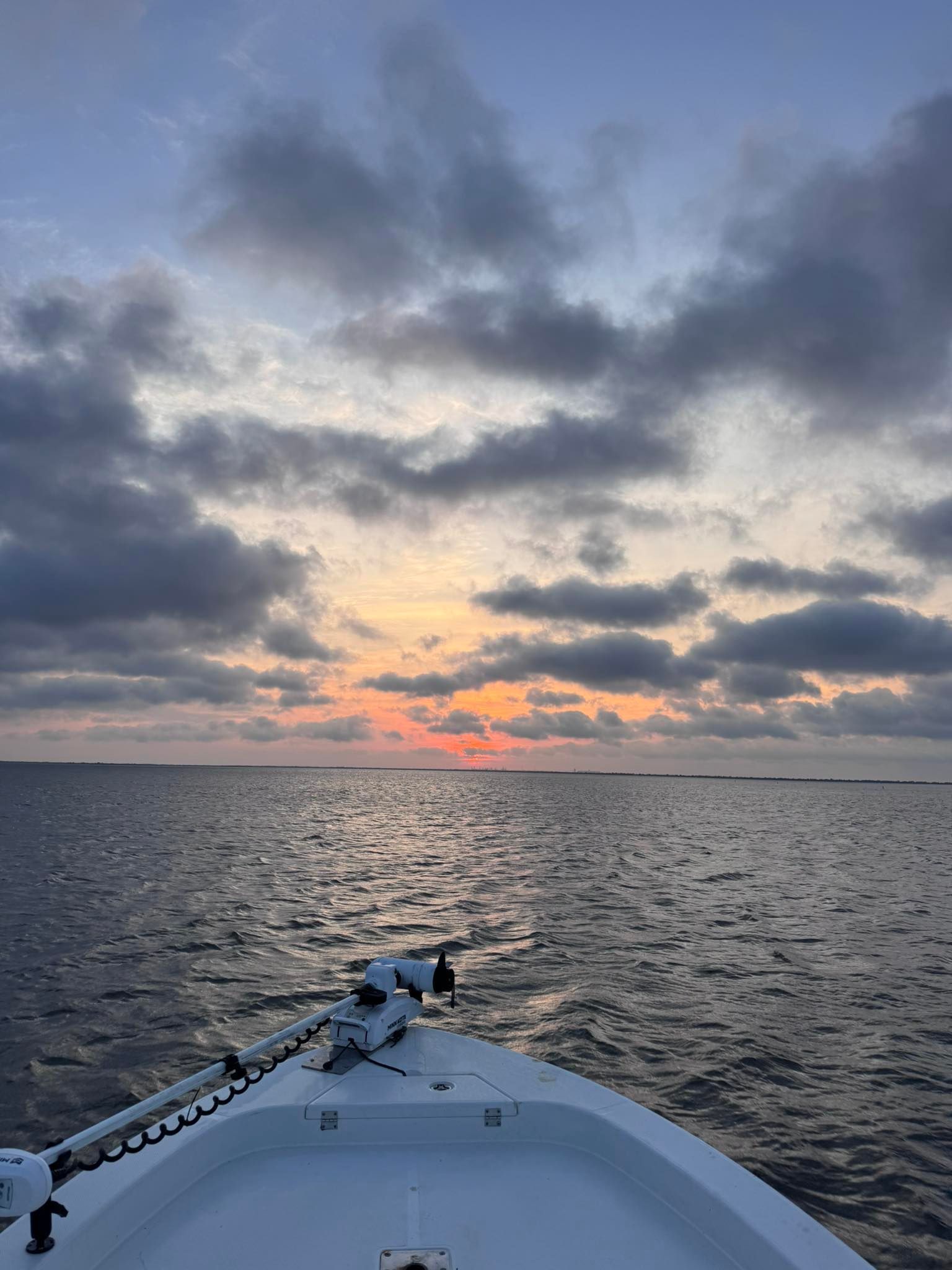 A boat is floating on top of a body of water at sunset.