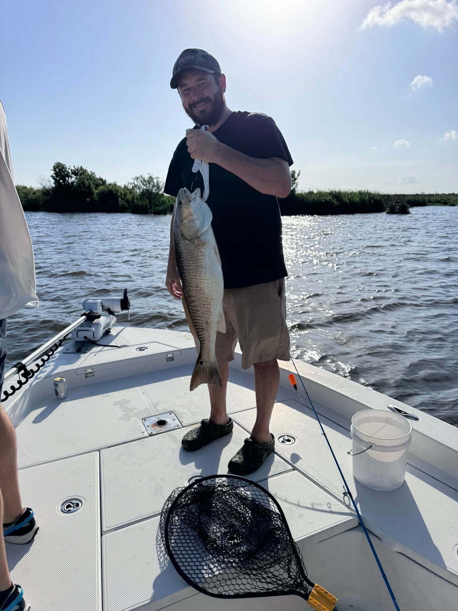 A man is standing on a boat holding a large fish.