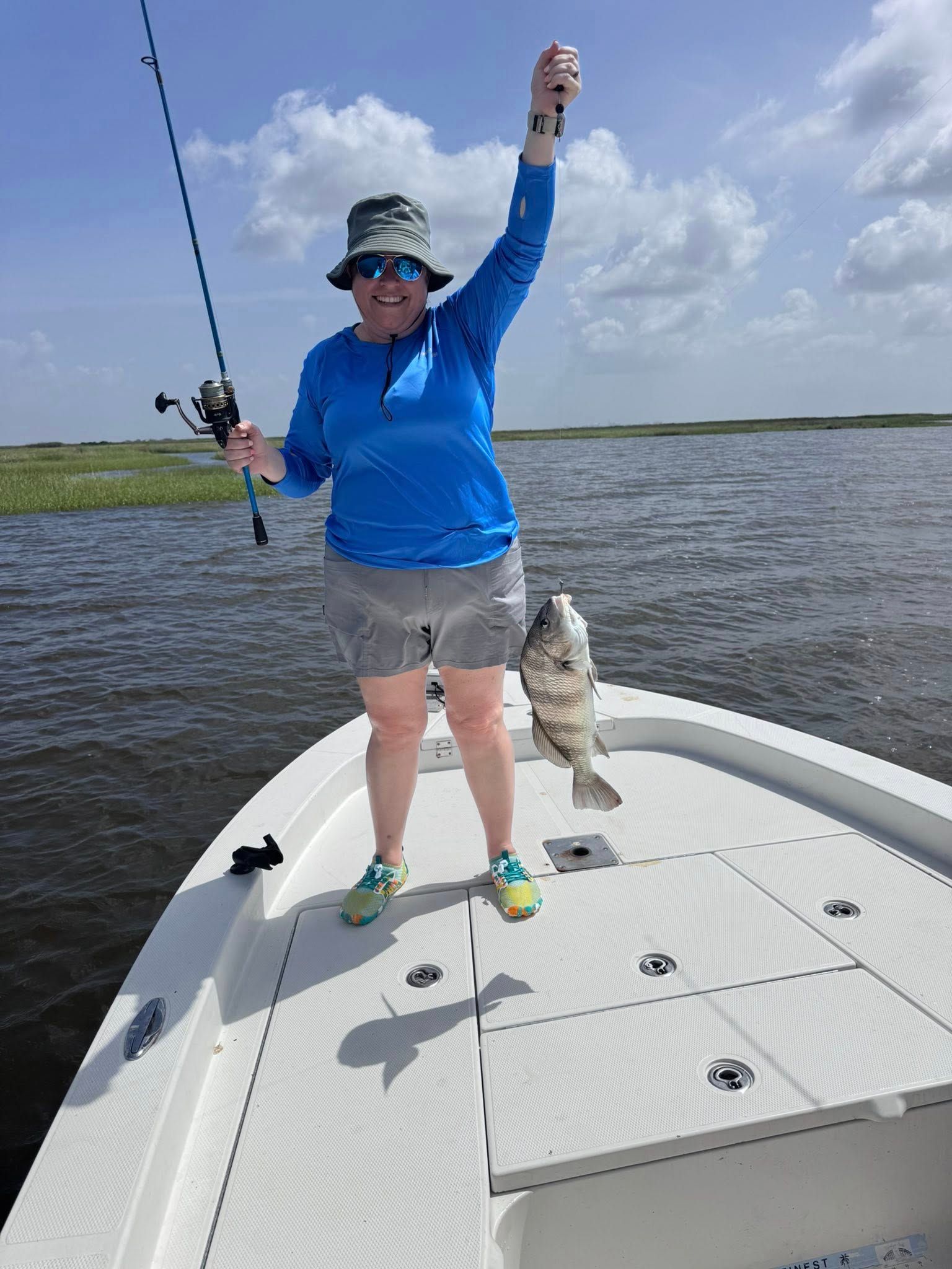 A woman is standing on a boat holding a fish.