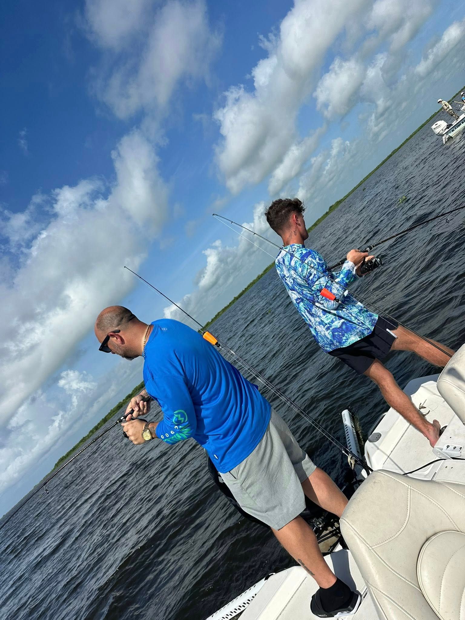 Two men are fishing on a boat in the water.
