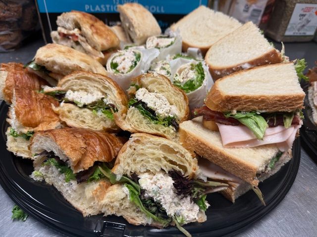 A tray of sandwiches and wraps on a table.
