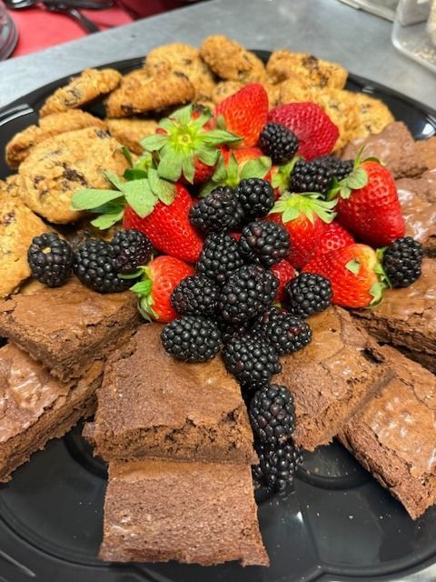 A black plate topped with brownies strawberries and blackberries