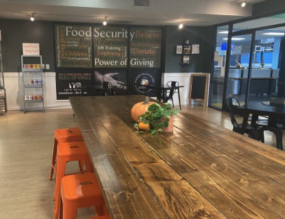 A long wooden table with a pumpkin on it in a room.