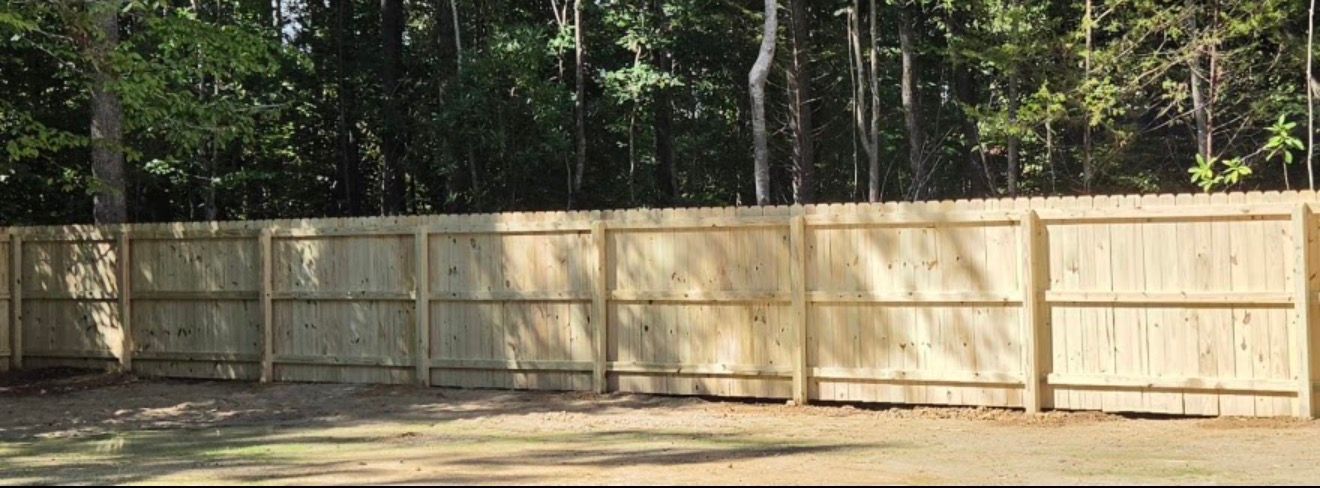 Wooden privacy fence along a wooded yard in daylight