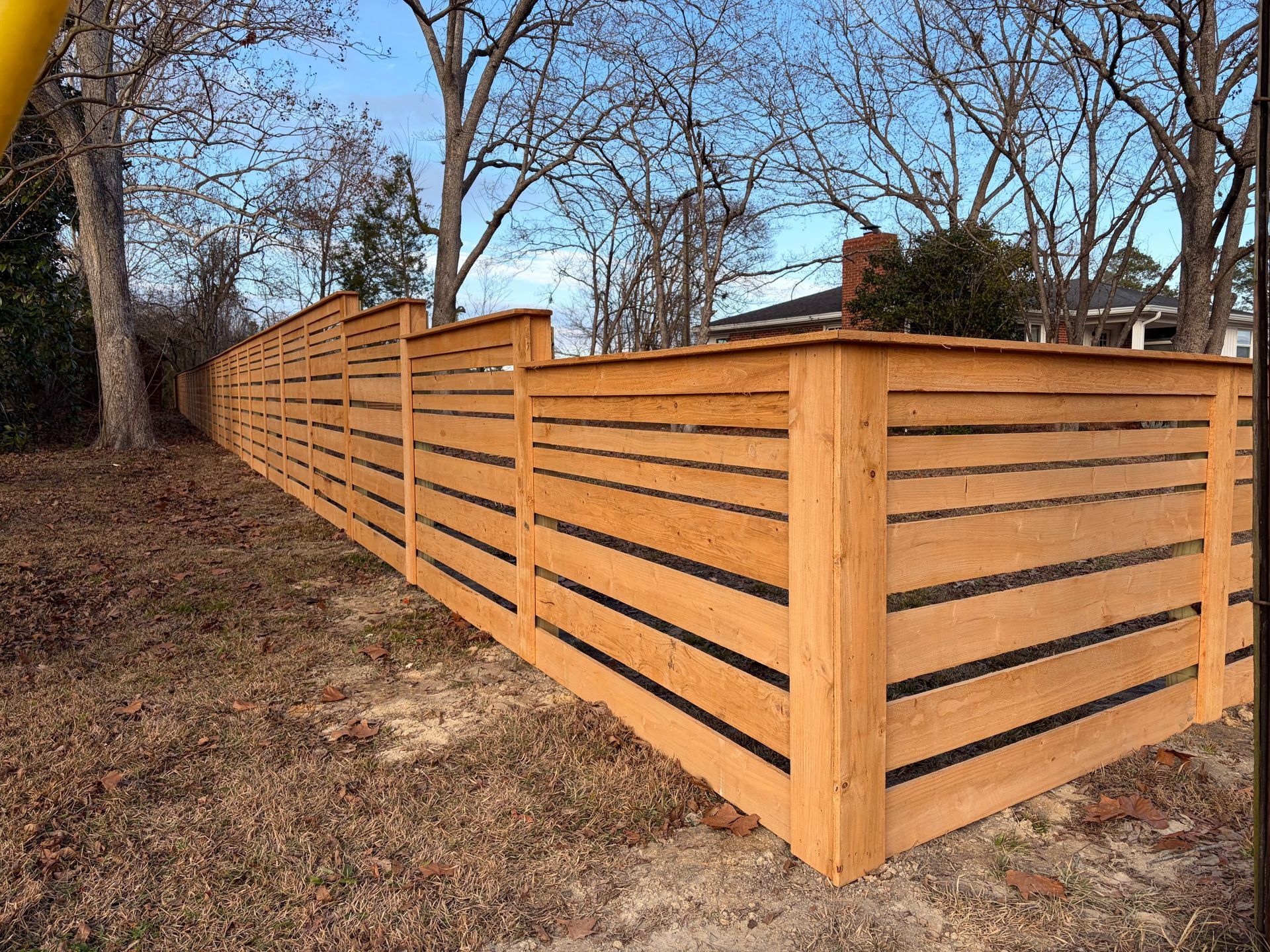 Wooden privacy fence along a wooded yard in late fall