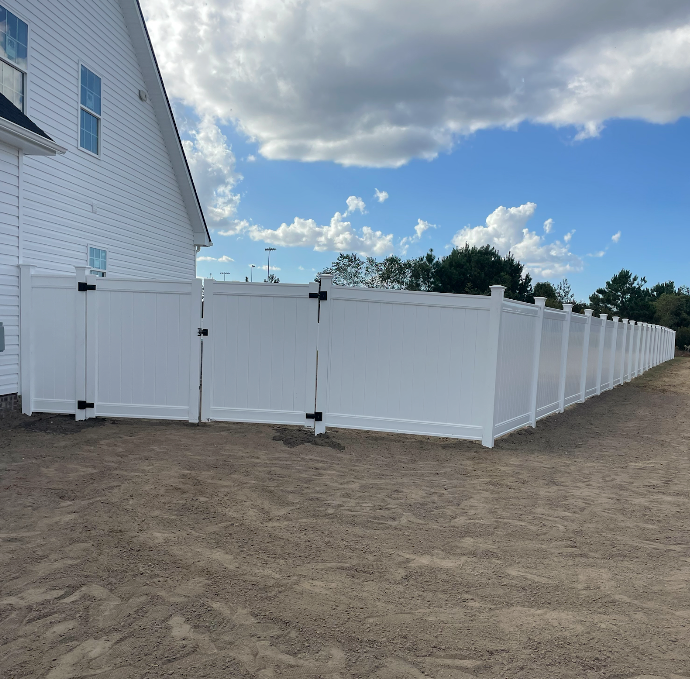 White vinyl fence surrounding a house on a sunny day.