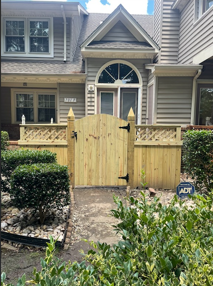 Wooden gate and fence in front of a two-story building.