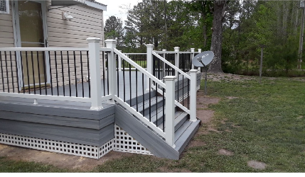 Deck with white and black railing, gray steps, and latticework skirting.
