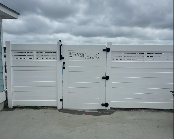 White vinyl fence and gate with black hardware under a cloudy sky.