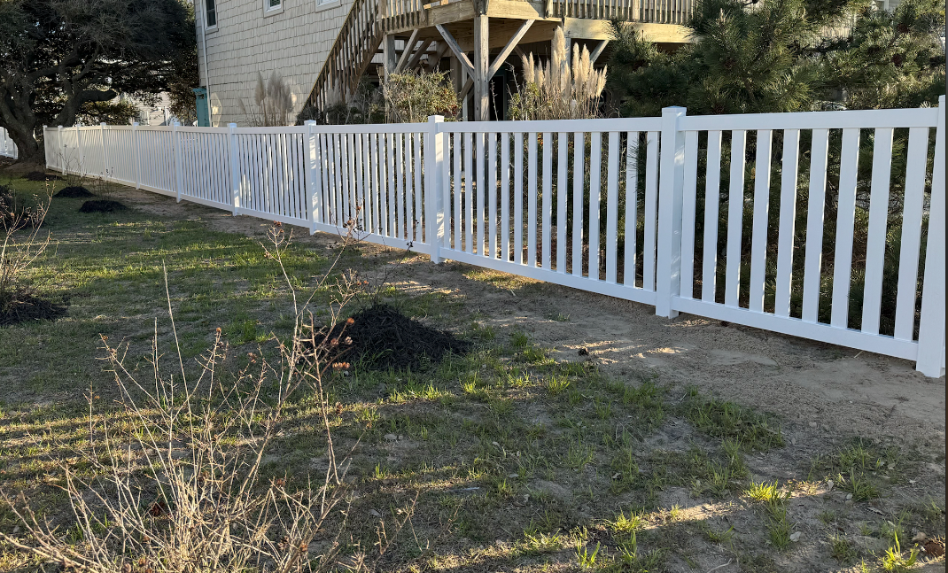 White picket fence along a yard, in front of a building.