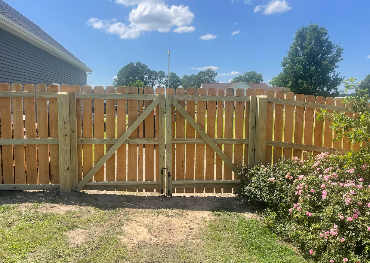 Wooden fence with gate, in a yard on a sunny day.