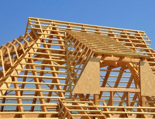 Wooden roof frame under construction against a blue sky.