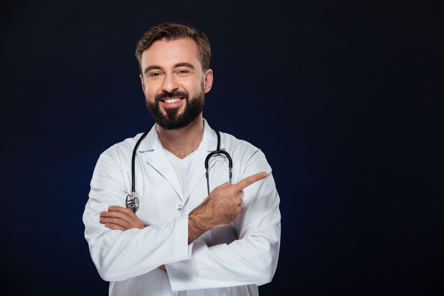 Medico com estetoscópio e jaleco sorrindo com os braços cruzados apontando para direita