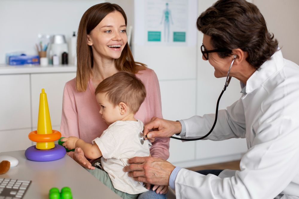 Médico examinando bebê com estetoscópio enquanto a mãe observa sorrindo, em ambiente pediátrico.