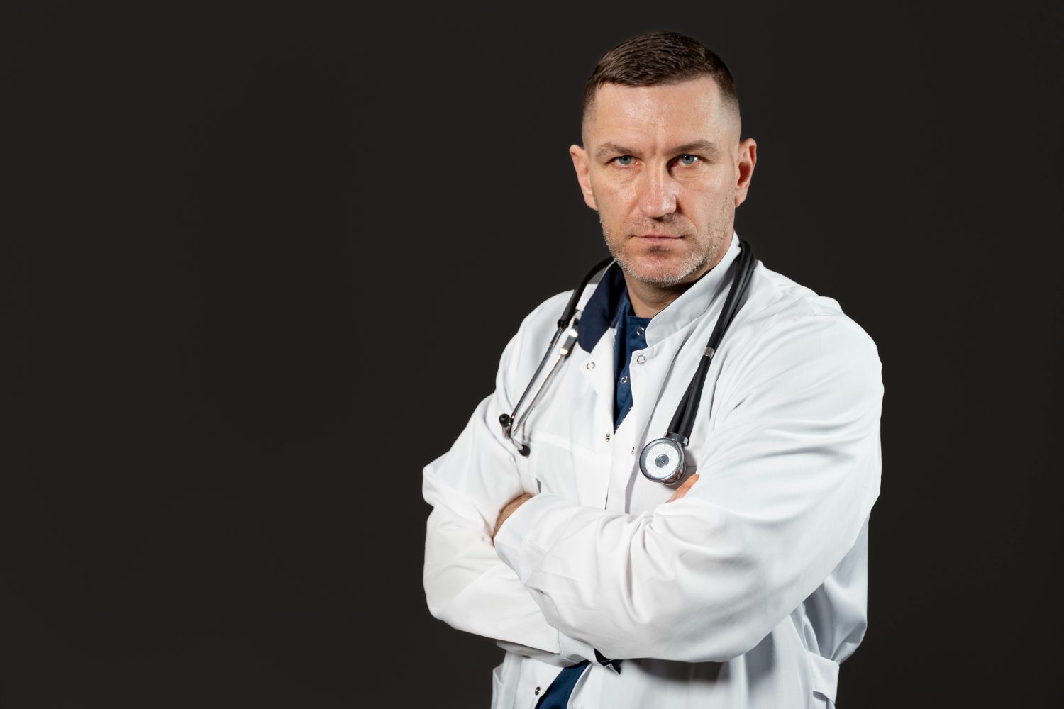 Medico bravo com estetoscópio e jaleco com os braços cruzados