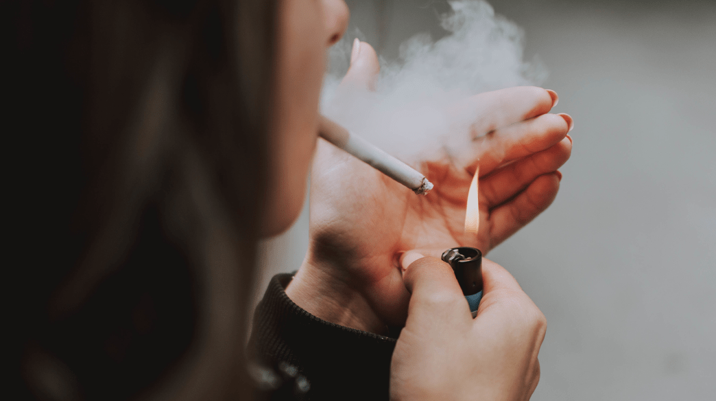 garota de costas acendendo um cigarro