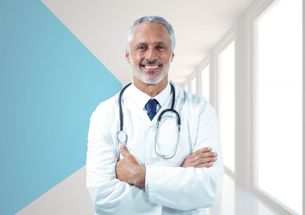 Medico com estetoscópio e jaleco sorrindo com os braços cruzados