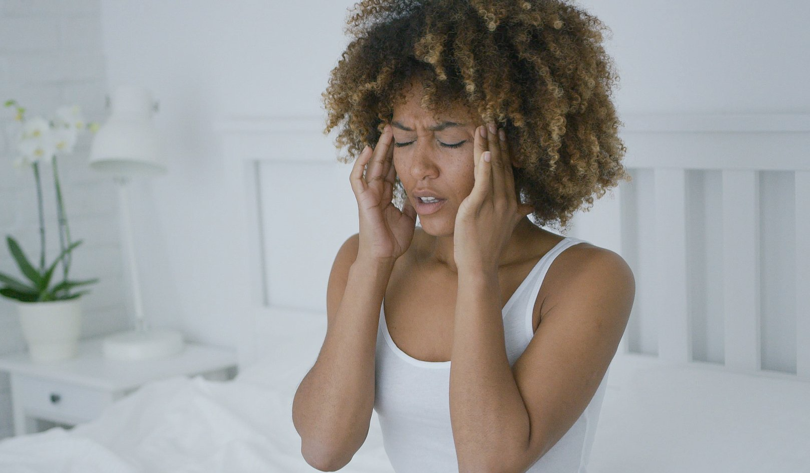mulher  na cama com dor de cabeça