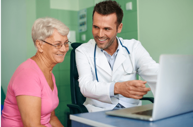 médico mostrando algo para uma senhora em um notebook 