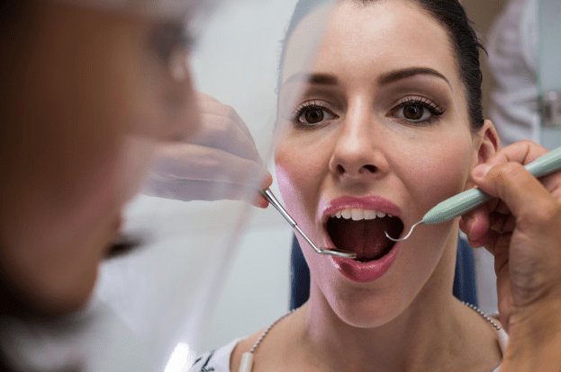 dentista examinando mulher com utensilios