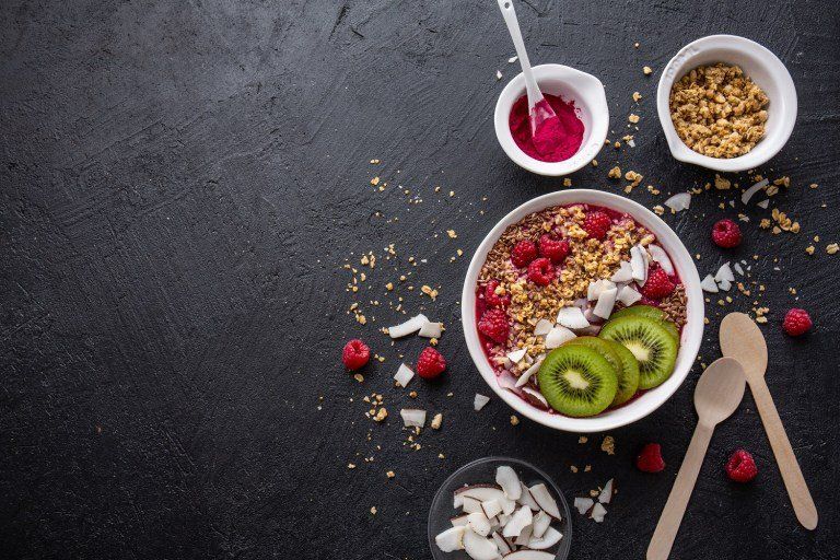 frutas e cereais em recipientes espalhados com fundo cinza escuro