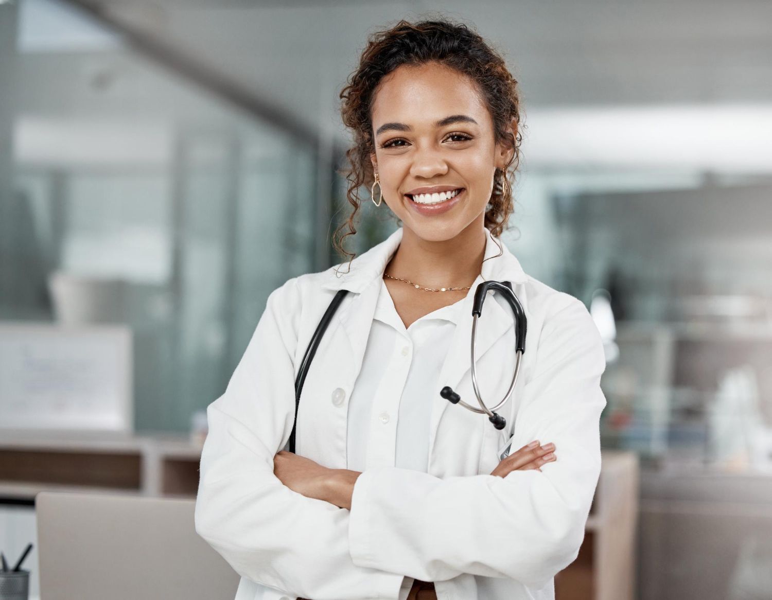 Medico com estetoscópio e jaleco sorrindo com os braços cruzados