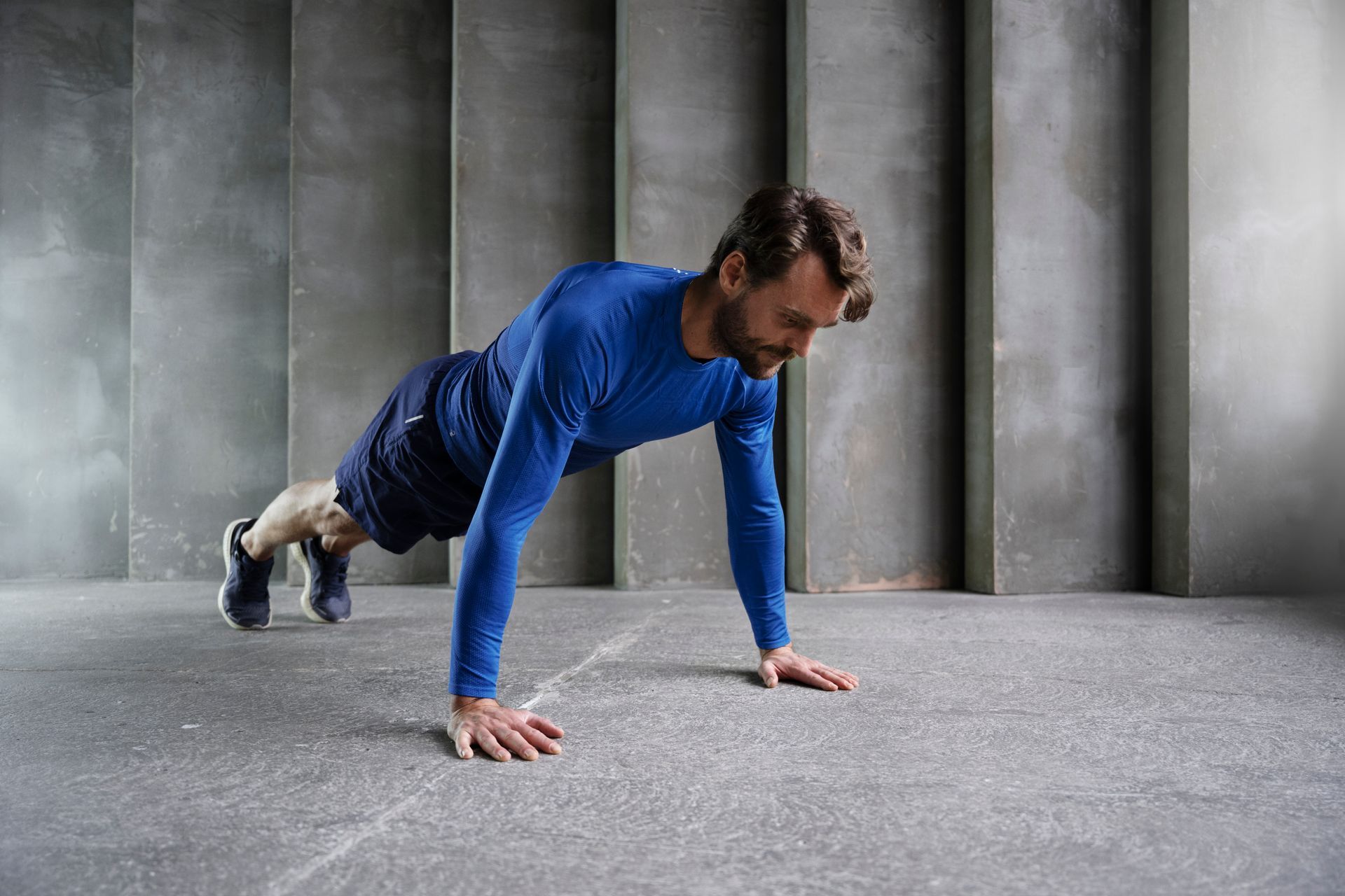 Homem se exercitando com flexão em ambiente interno, representando rotina fitness.