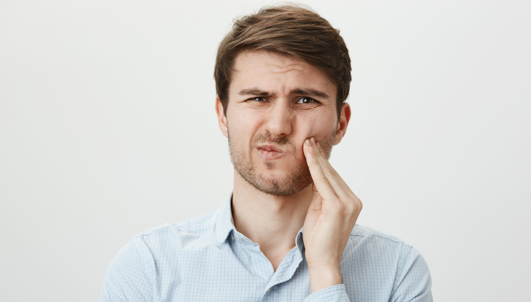 homem com mão no rosto com dor de dente e fundo branco
