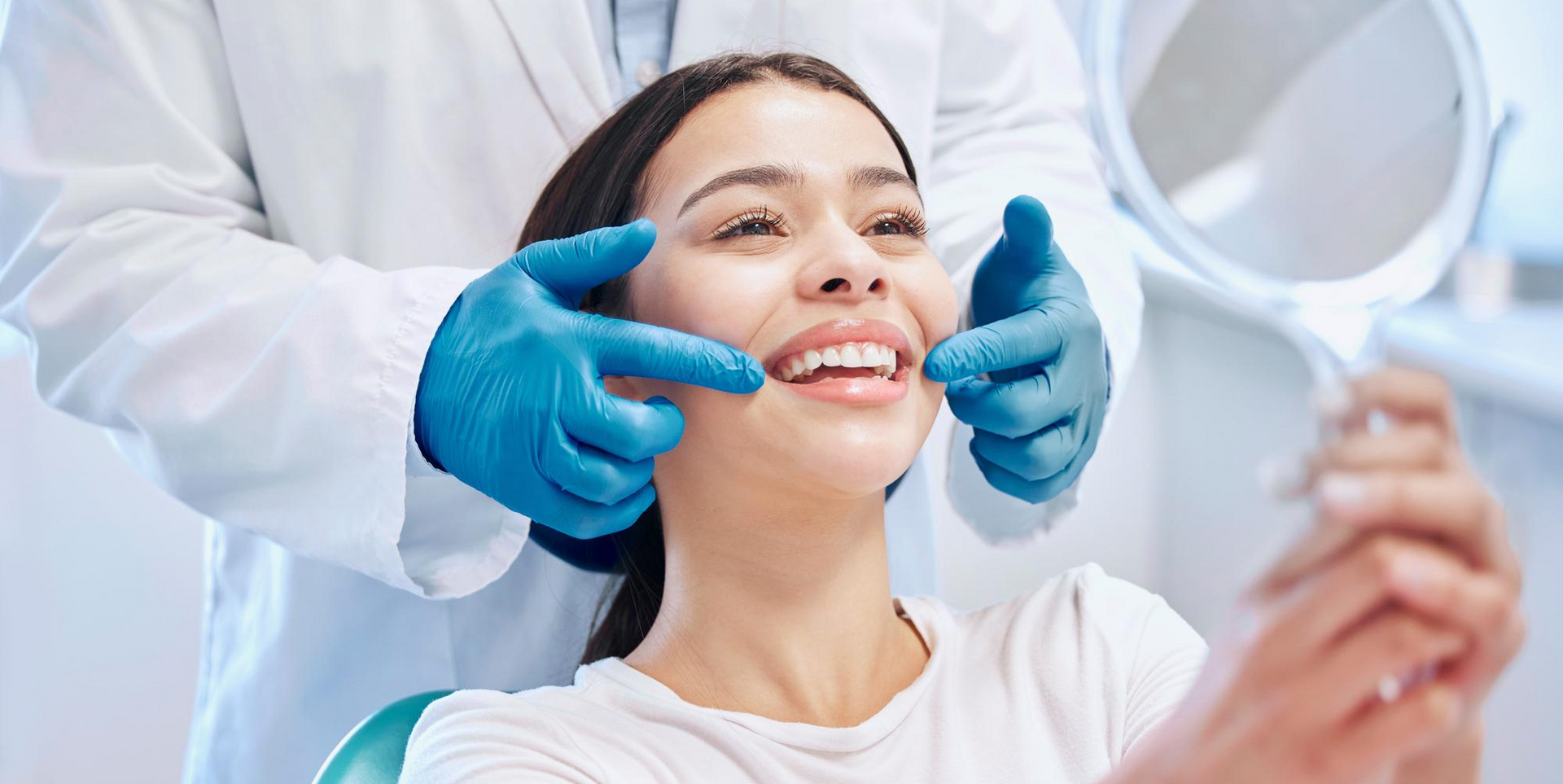 garota no dentista sorrindo com dentista com luvas azuis atras dela