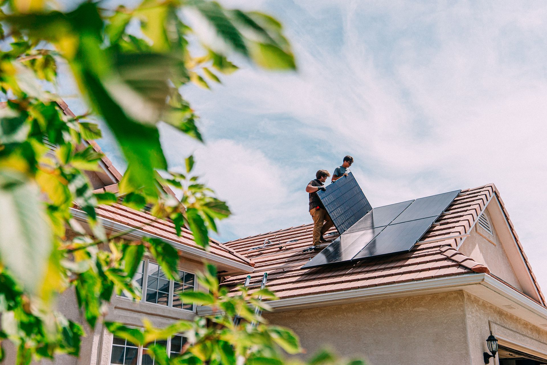 Two men are installing solar panels on the roof of a house.