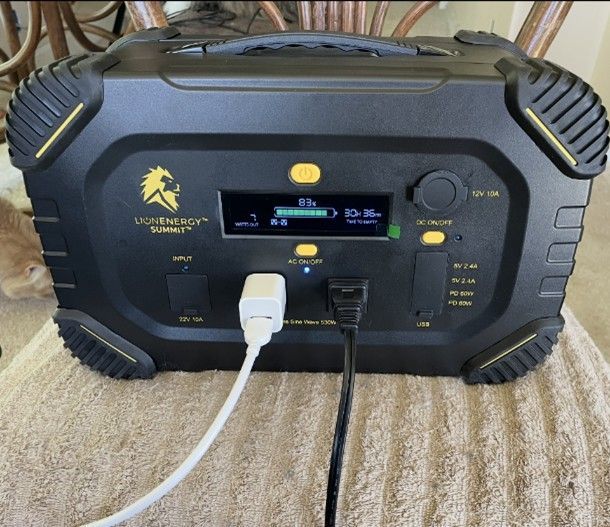 Black portable power station with digital display and plugged-in cables.