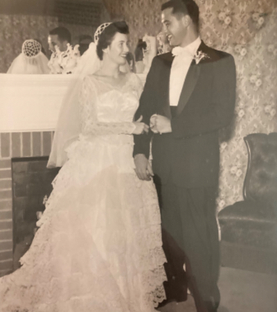 Bride and groom posing at a wedding, holding hands indoors by a fireplace
