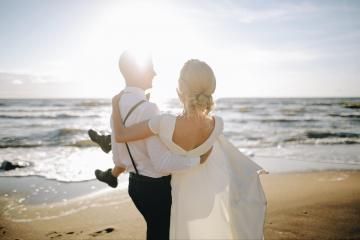 Couple embracing on a beach at sunset with ocean waves in the background