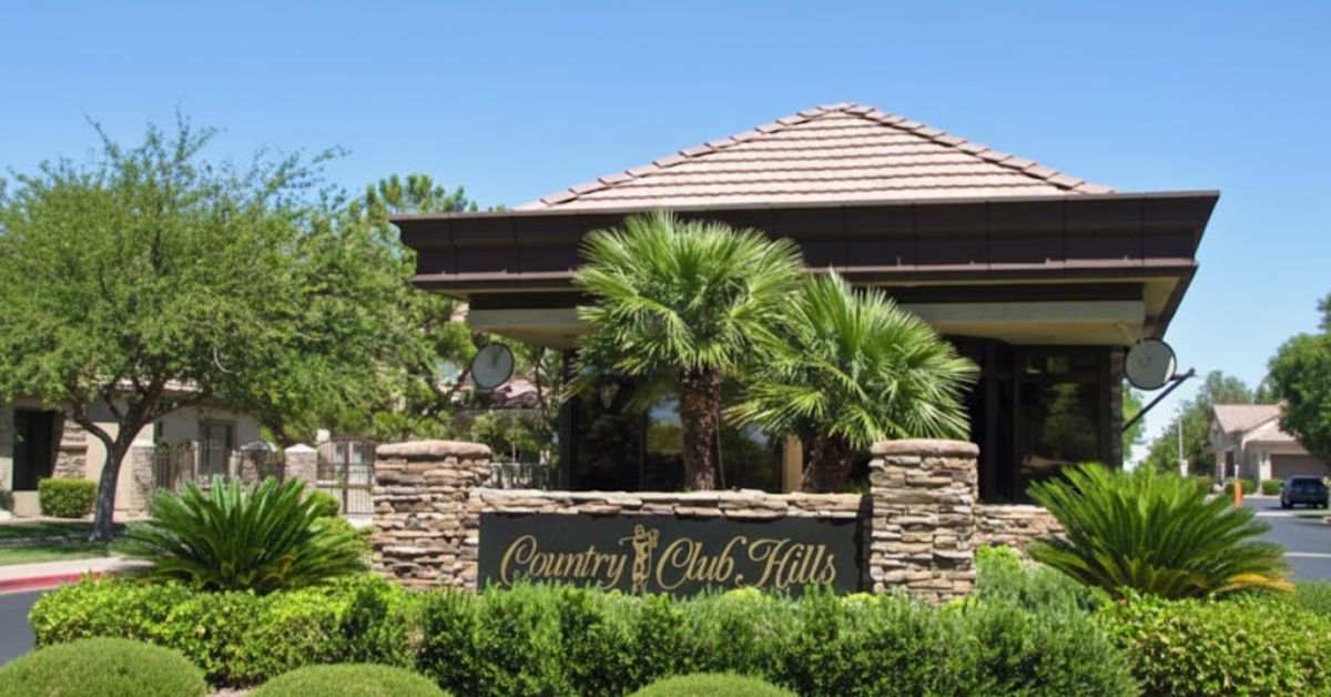 Entrance sign to Country Club Hill with palm trees and a tiled roof.
