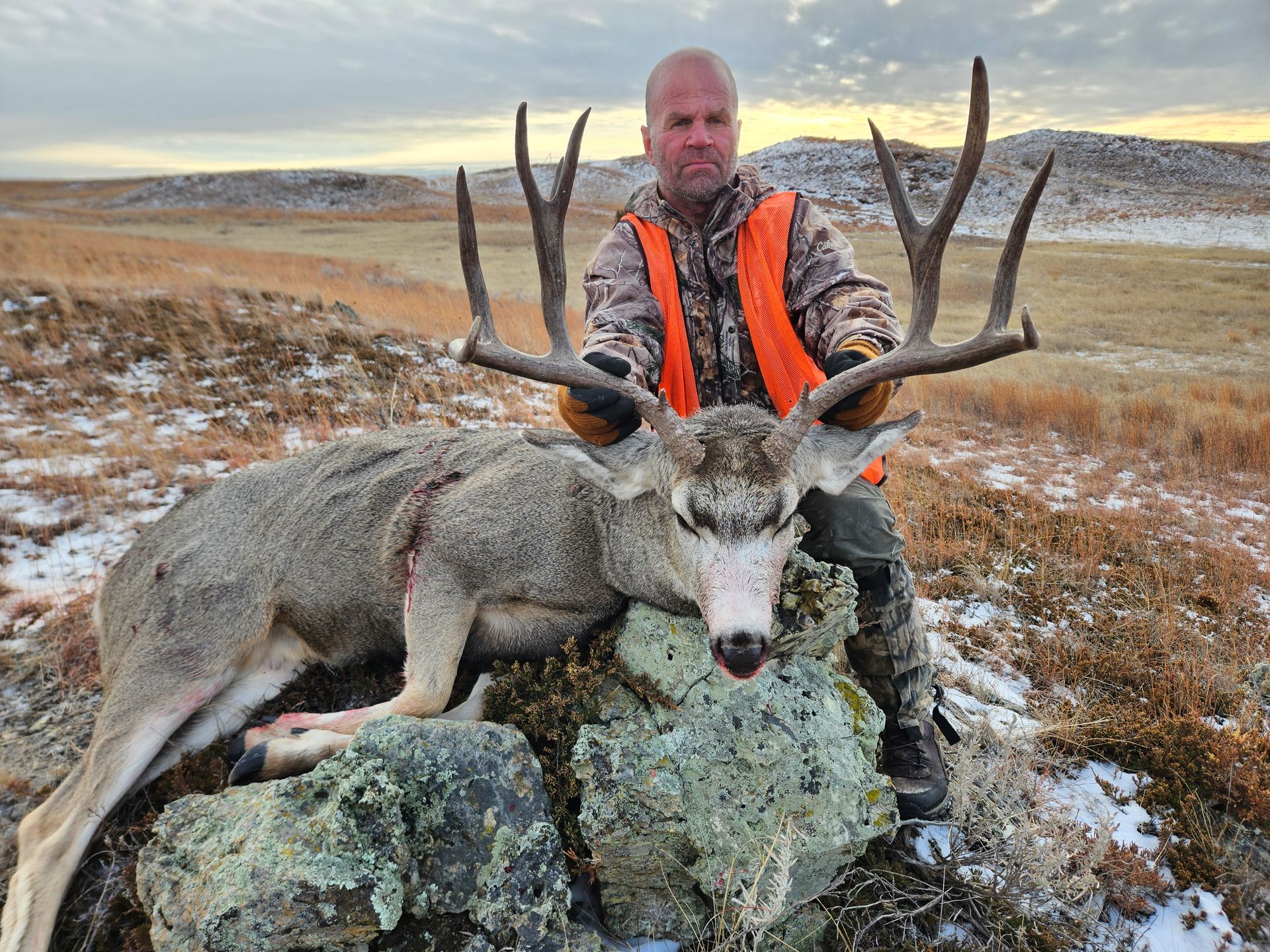 a man holding the antlers of a dead deer