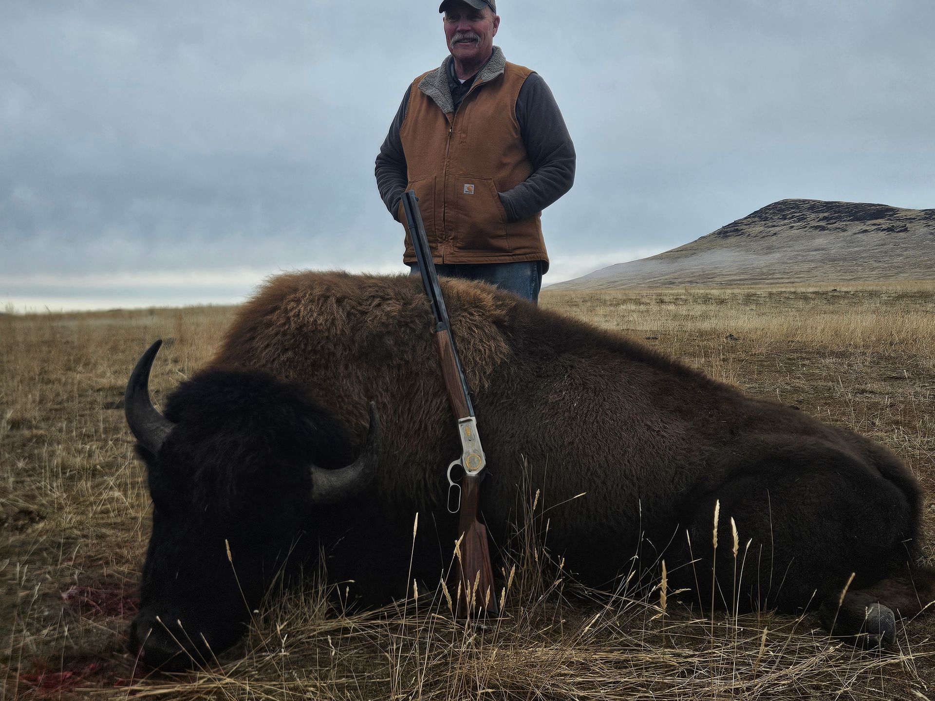A man standing with a dead bison