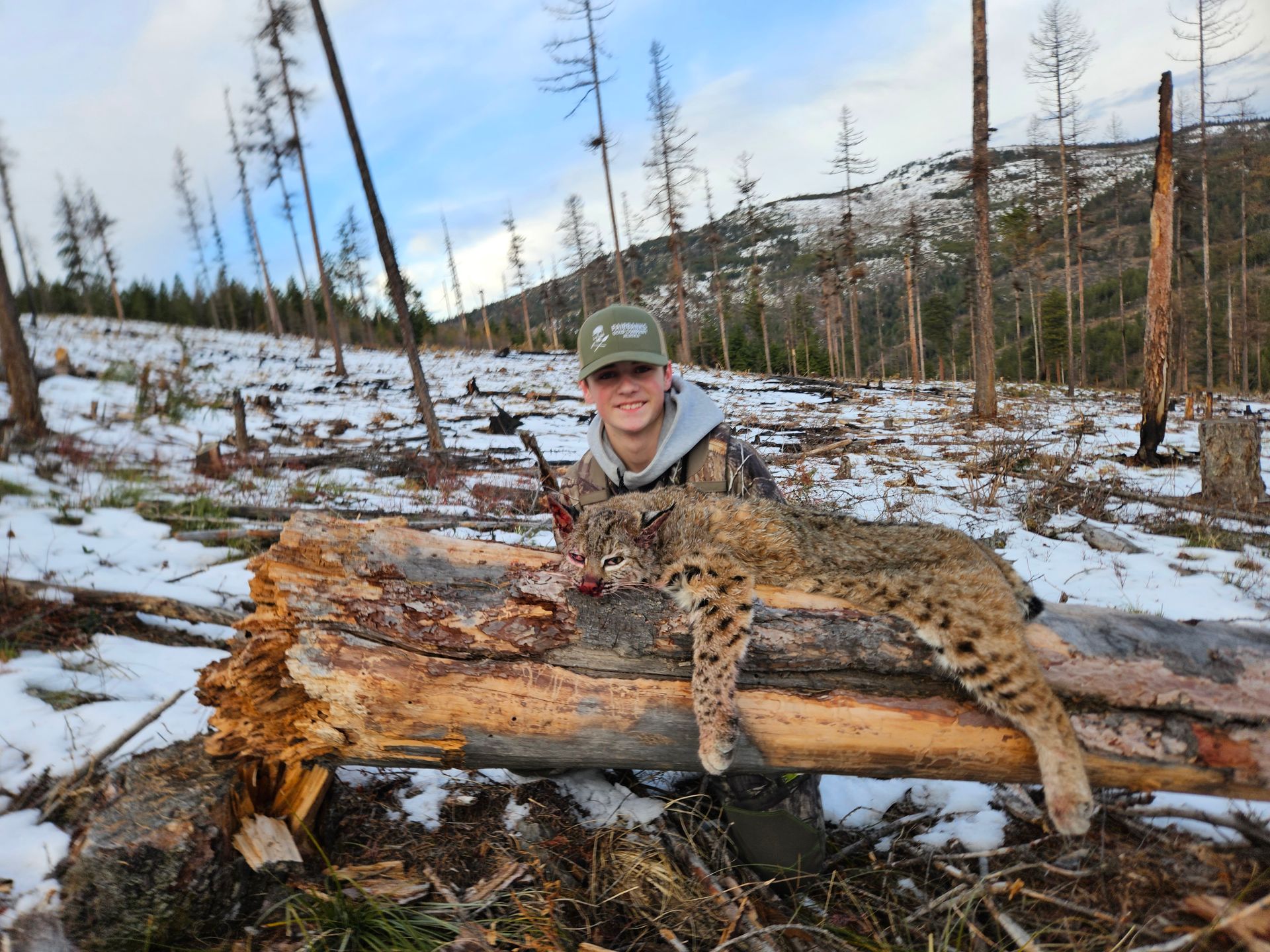 A man is posing next to a dead bobcat
