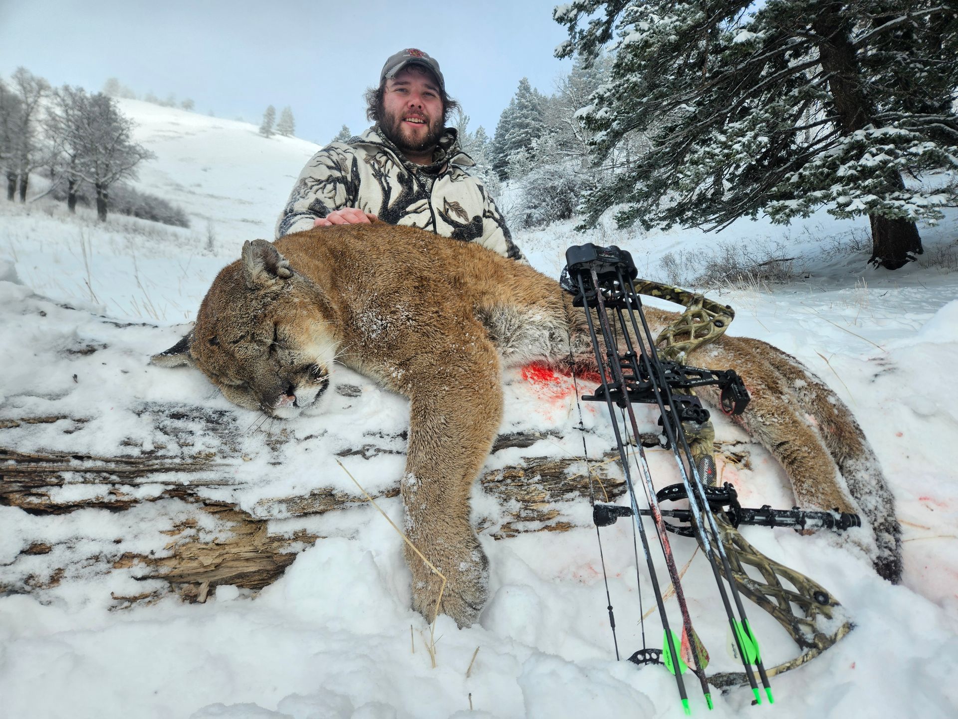 A man posing with a dead mountain lion