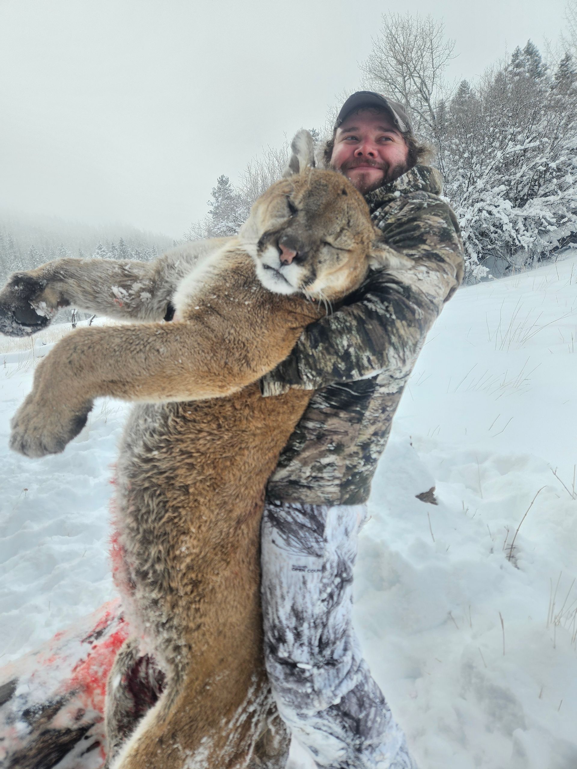 A man holding up a dead mountain lion