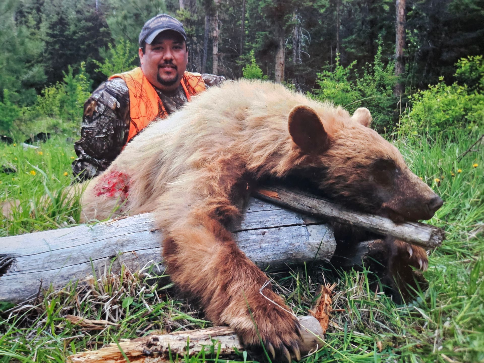 A man posing with a dead brown bear