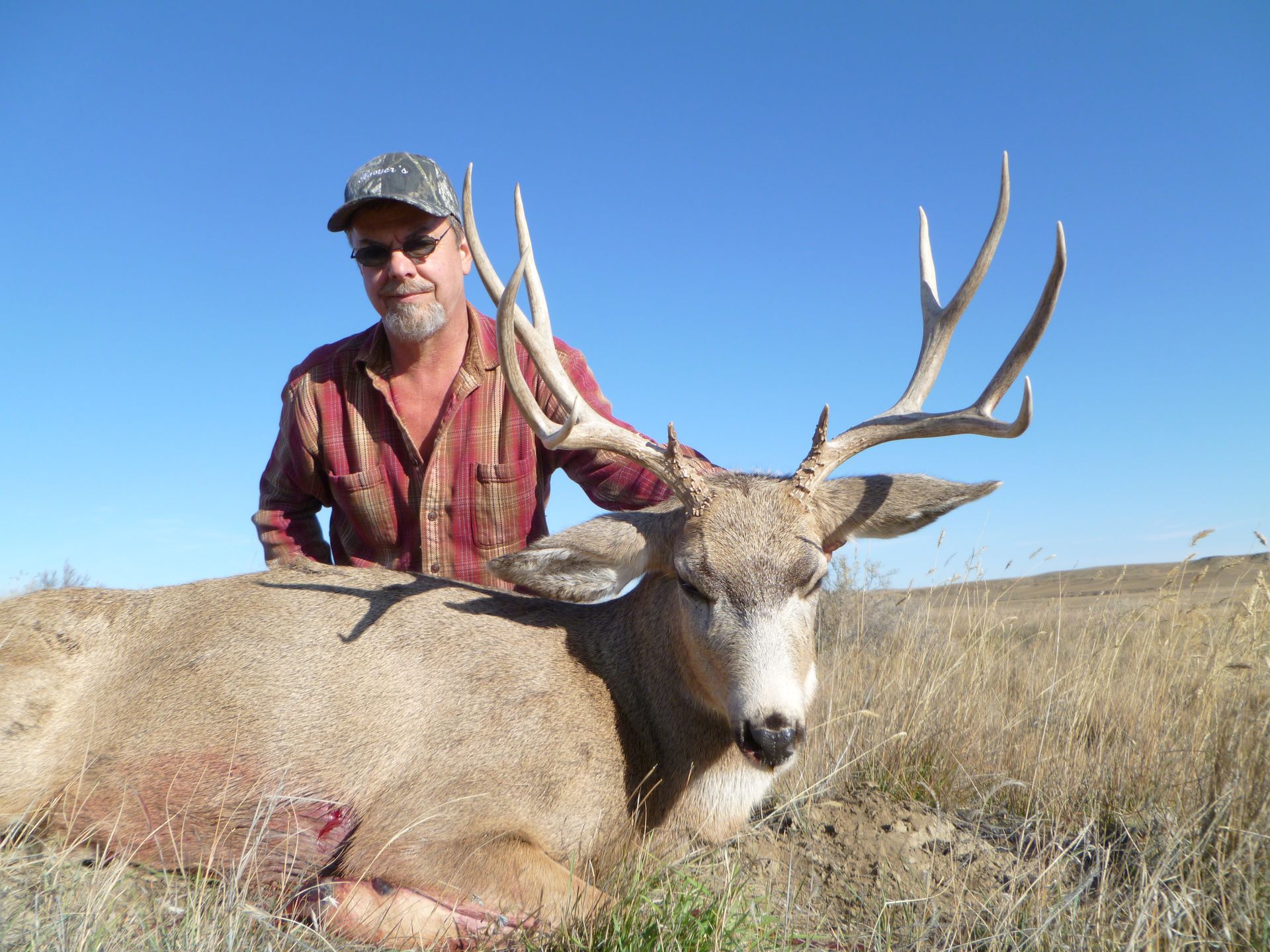 A man posing next to a dead deer