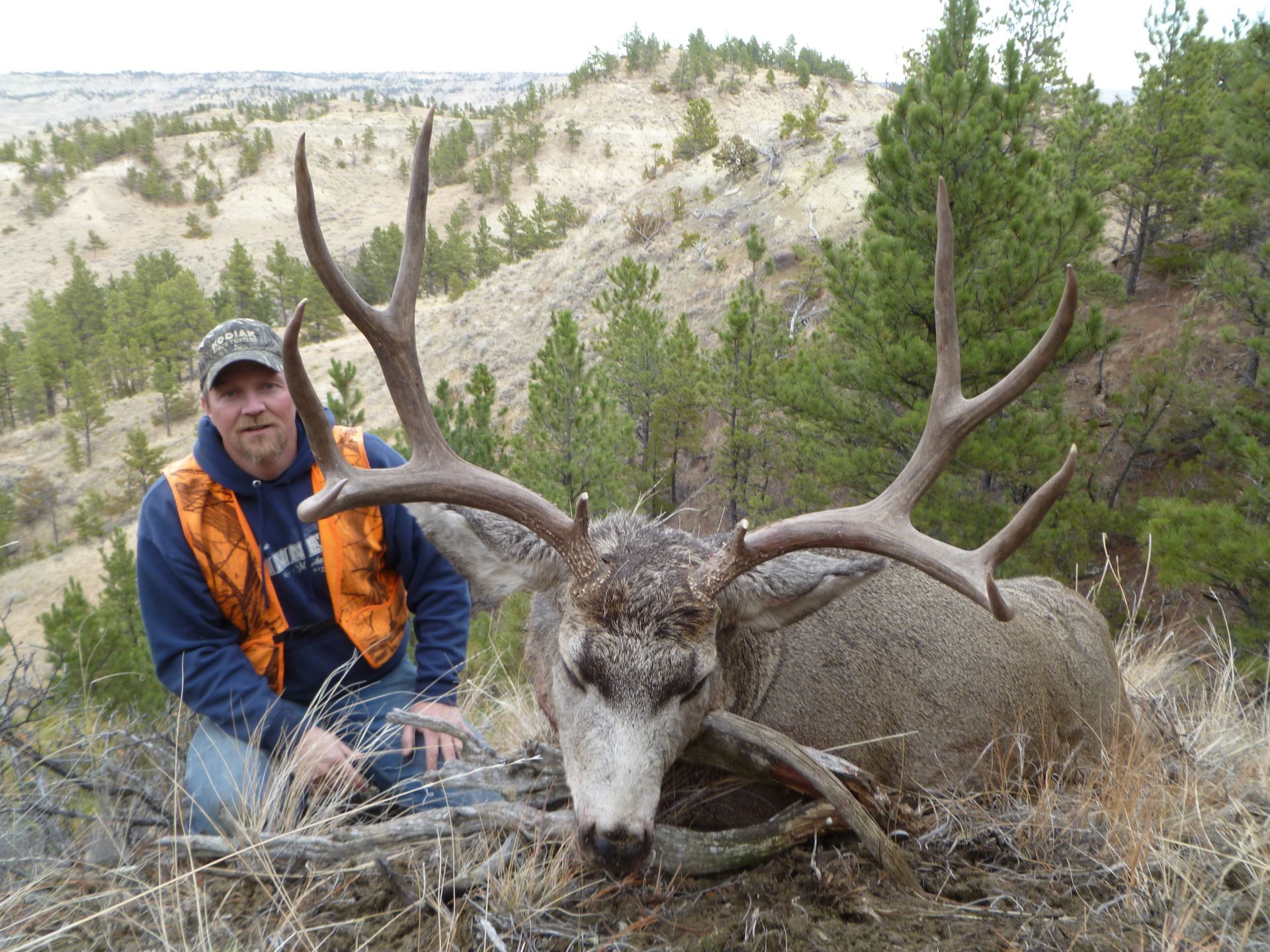 A man posing next to a dead deer