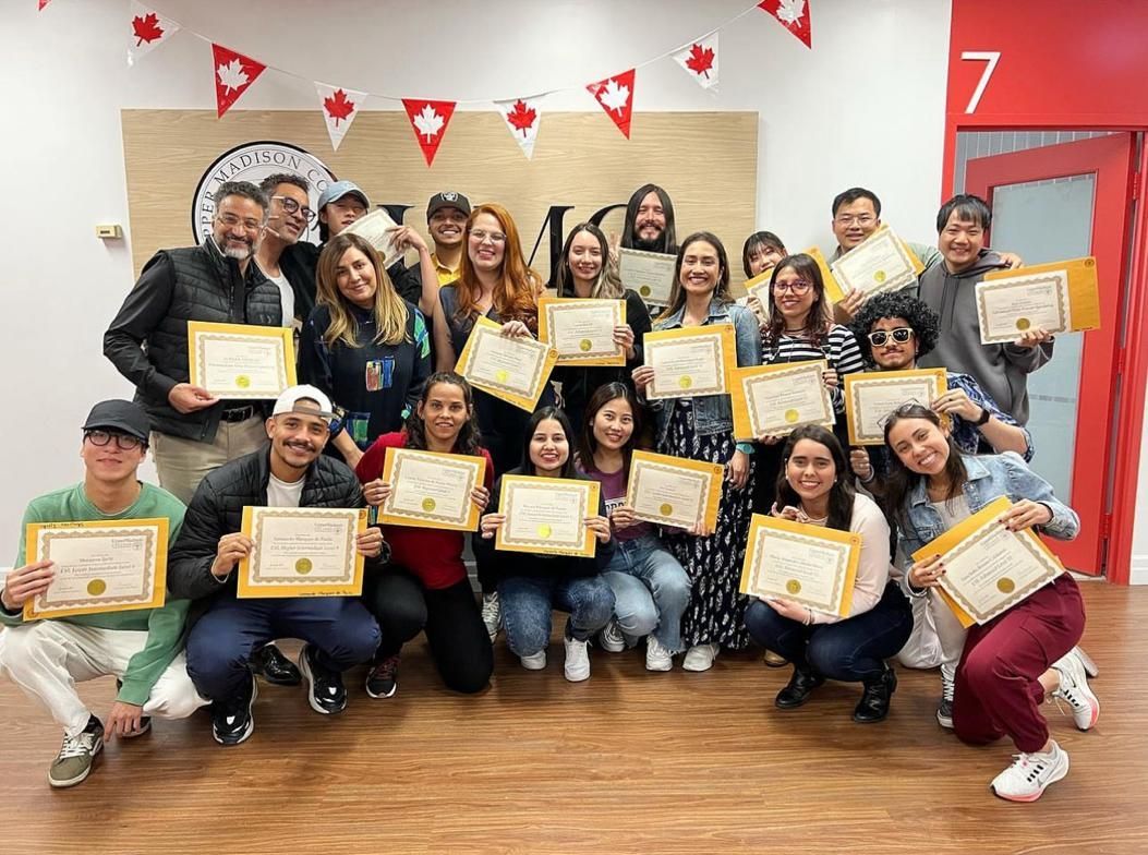 Group of people holding certificates, celebrating in a room decorated with flags.