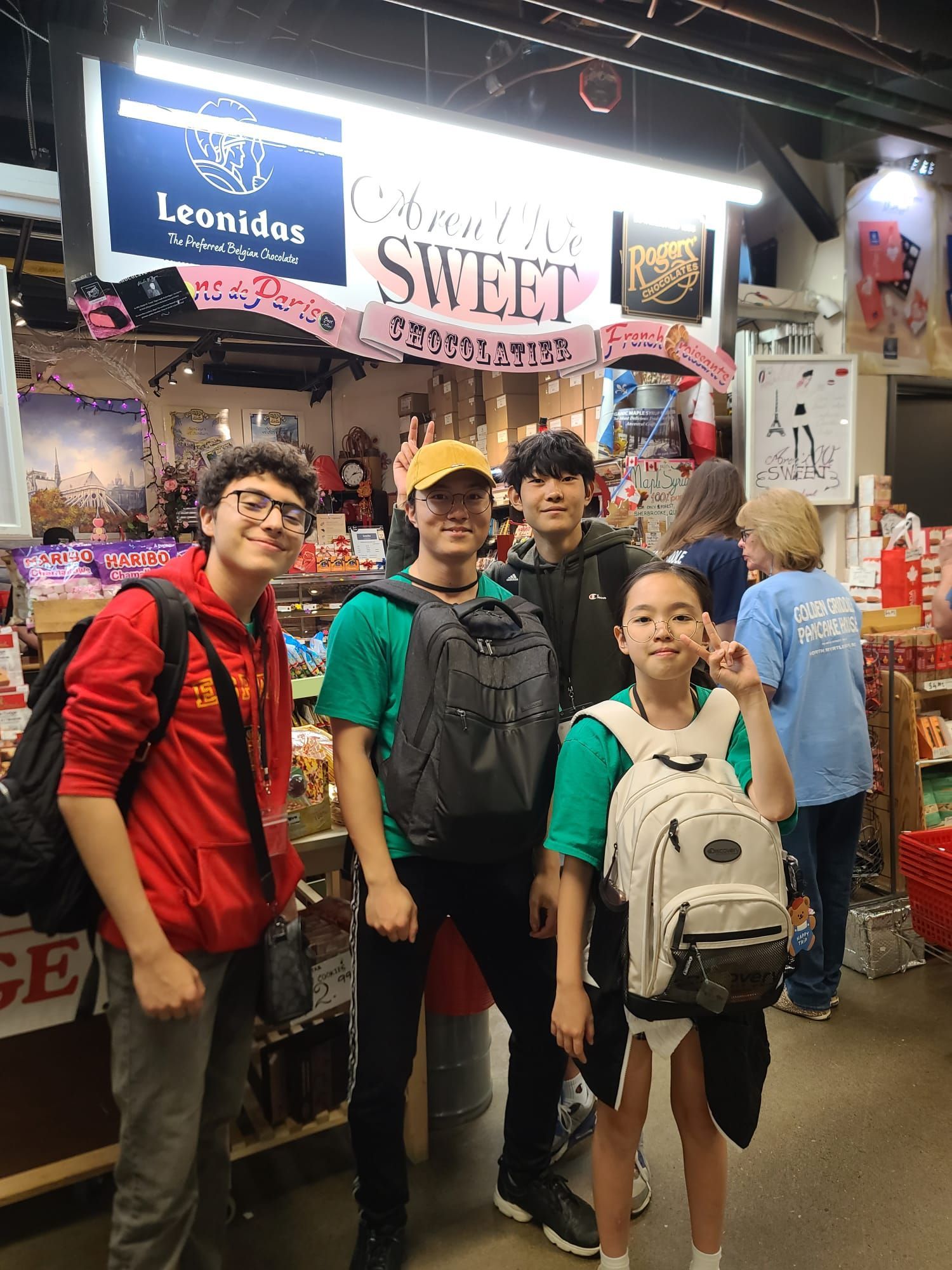 Group of people in front of a candy store display. A sign says 