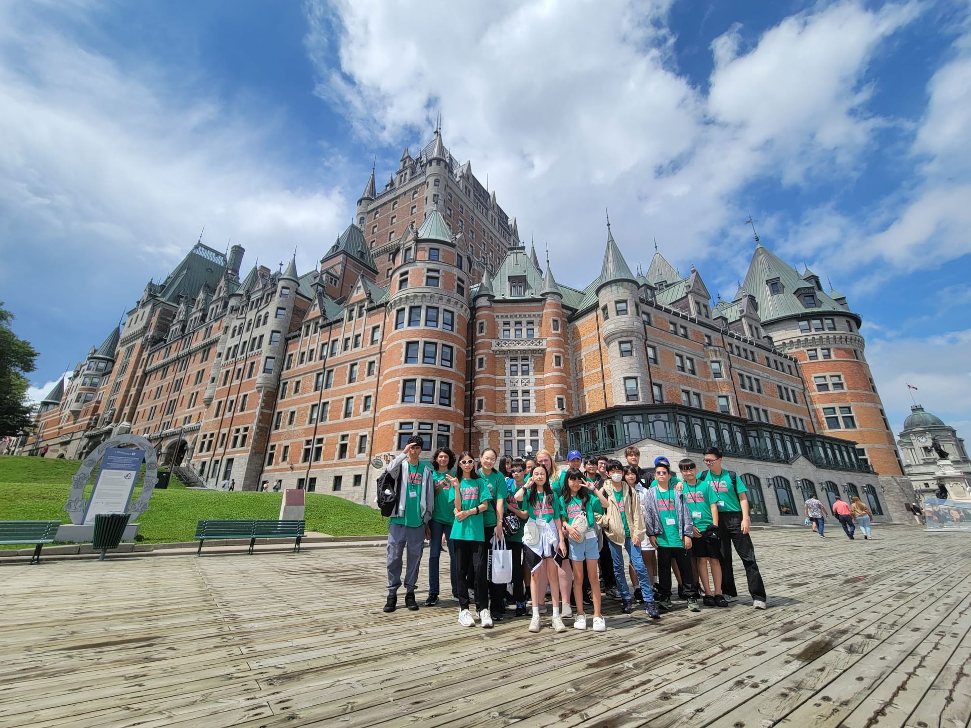 Group of people in green shirts in front of the Château Frontenac hotel, Quebec City. Sunny day, blue sky.