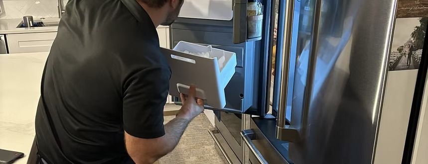 A man is working on a refrigerator in a kitchen.
