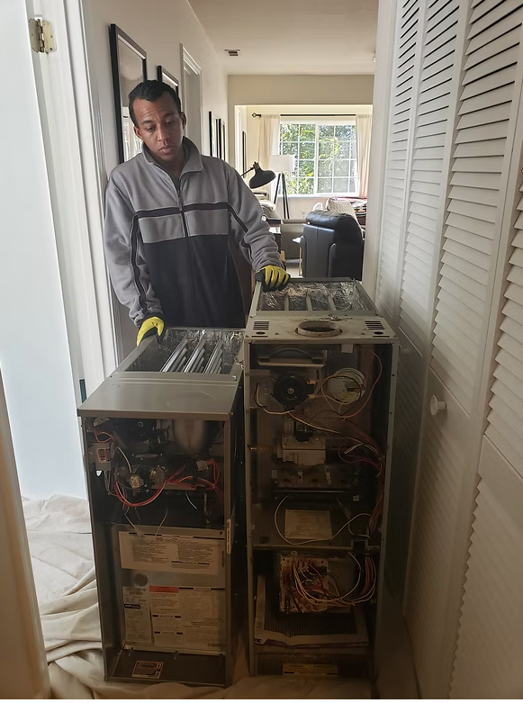 A man is working on an air conditioner in a hallway.