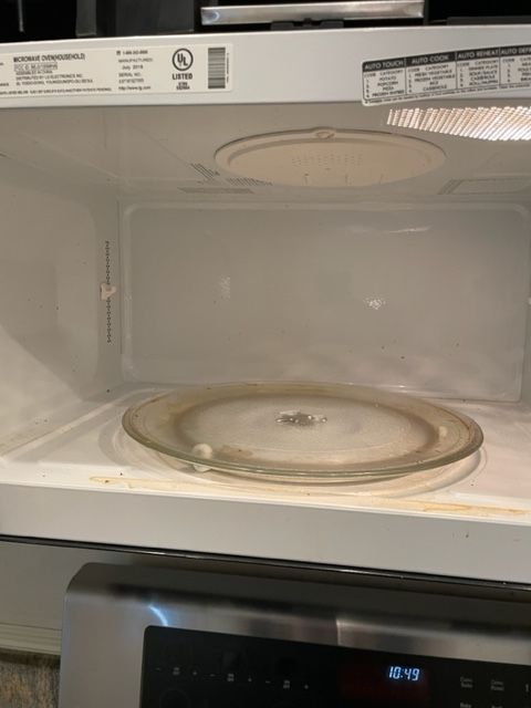 Inside of an open, clean microwave with a glass turntable and a stainless steel oven door visible.