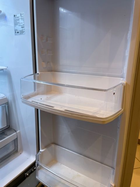 Open refrigerator door with empty white interior and clear shelves.